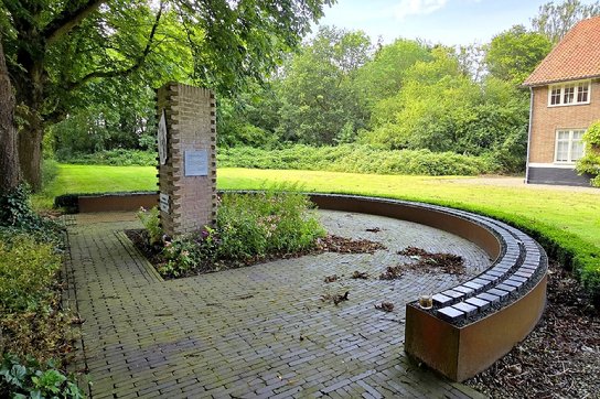 The image shows a serene, manicured garden with a circular memorial structure, surrounded by vibrant green foliage and brick pathways.
Door AI gegenereerde inhoud is mogelijk onjuist.