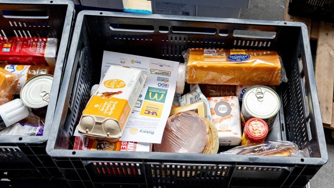Plastic kratten gevuld met verschillende voedingsmiddelen zoals brood, eieren, ingeblikt voedsel en zout.