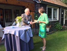 Juli 2017: In de ambstwoning van Kiki en Elbert Roest, midden in het Hertenkamp in Laren, vond de bestuursoverdracht plaats. De nieuwe voorzitter, Marius Vis, geeft Kiki een presentje om te bedanken voor de gastvrijheid.