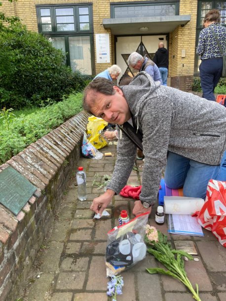 Op de foto is één van de Rotaryleden afgebeeld die bezig is te Stolpersteine te poetesen bij het Joodse Weeshuis