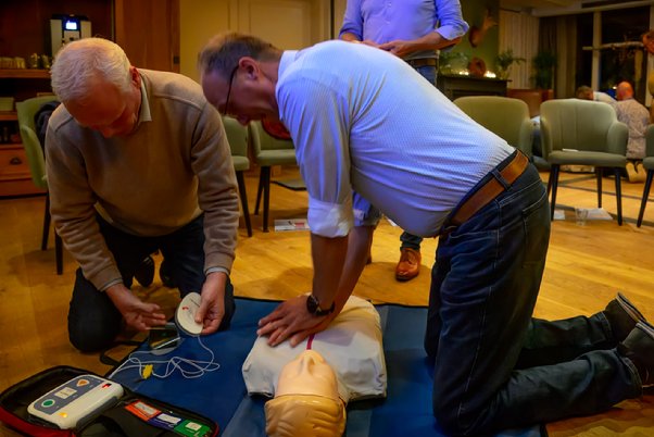 A group of men practicing cpr on a mannequin

Description automatically generated