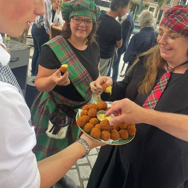 Kan een afbeelding zijn van 3 mensen, kroket, scotch egg en dirndl